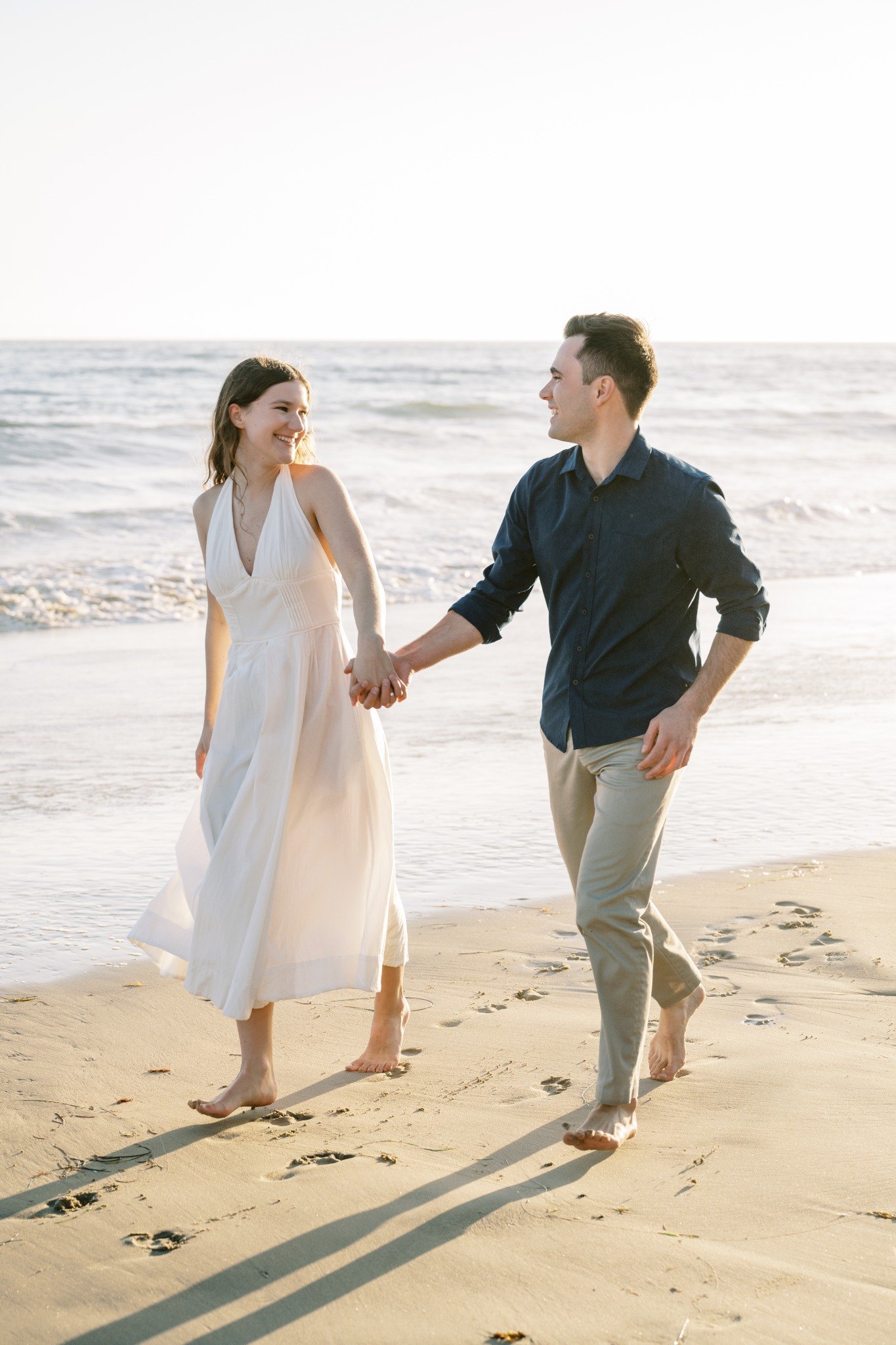 Molly and Nick running hand in hand on the beach